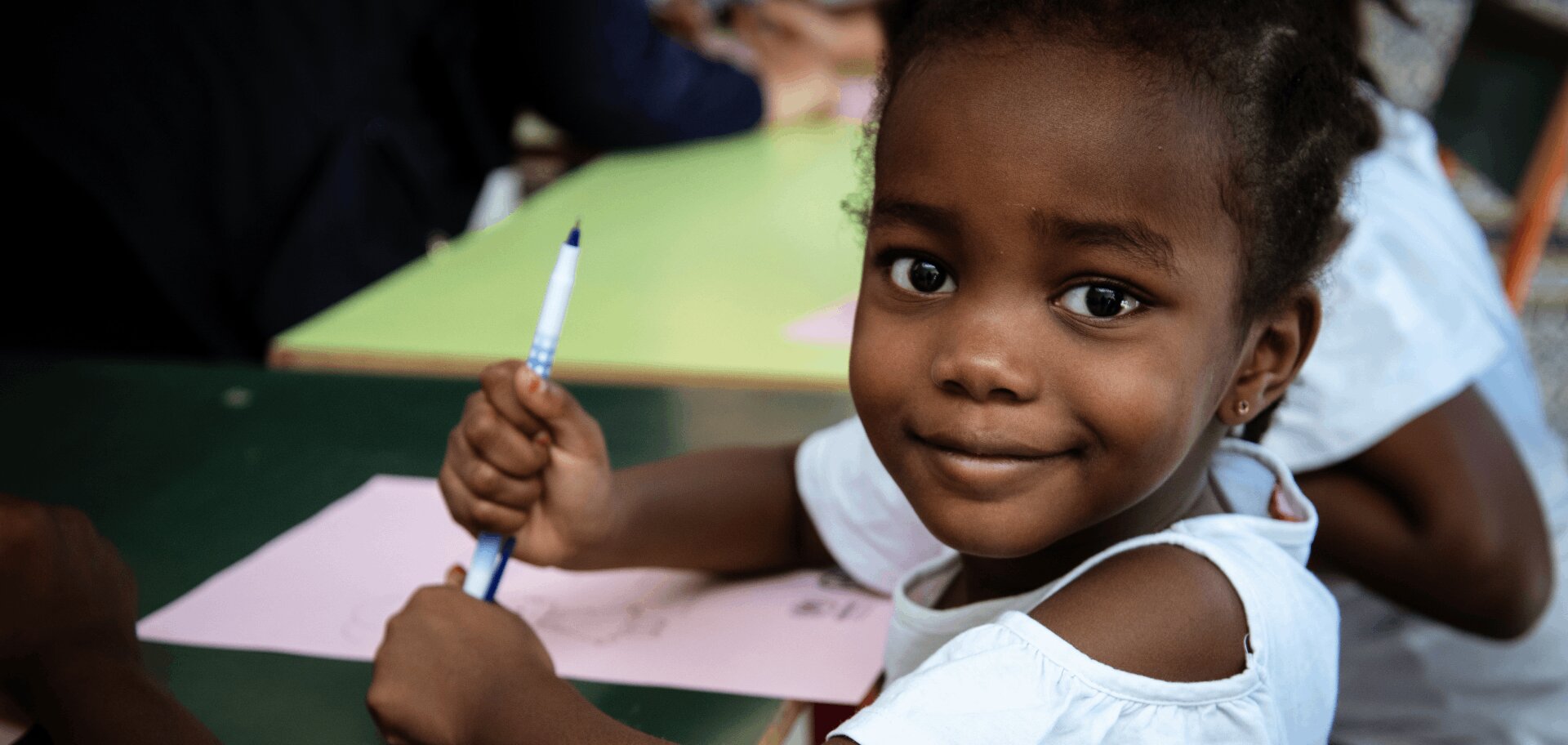 cta_tunisia_eight-year-old-girl-sits-at-desk-and-smiles-at-camera