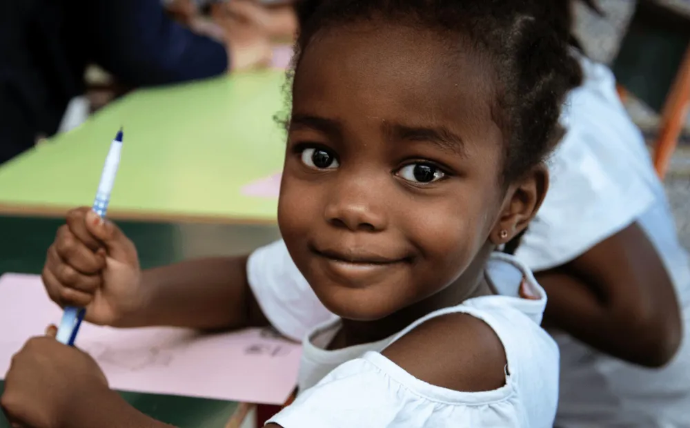 cta_tunisia_eight-year-old-girl-sits-at-desk-and-smiles-at-camera