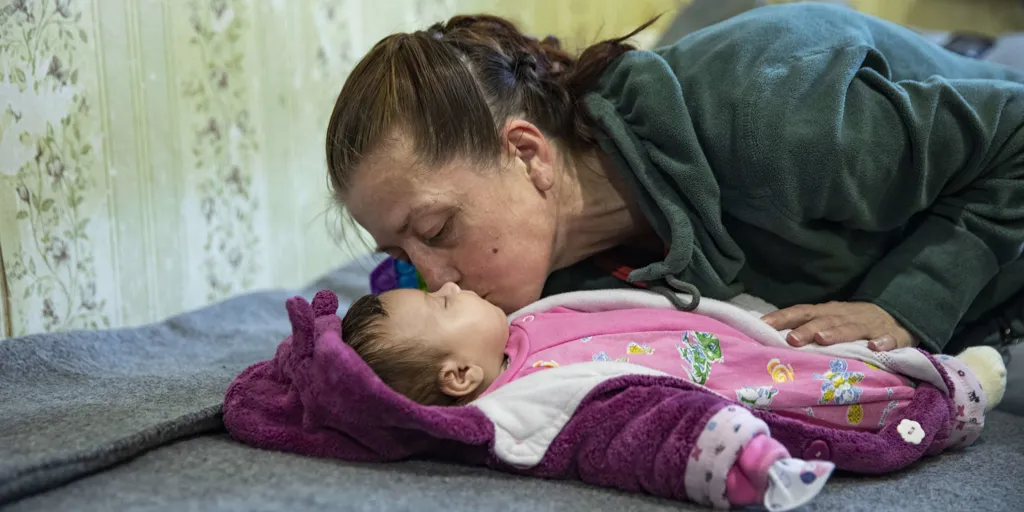 Displaced Ukrainian mother kissing her baby