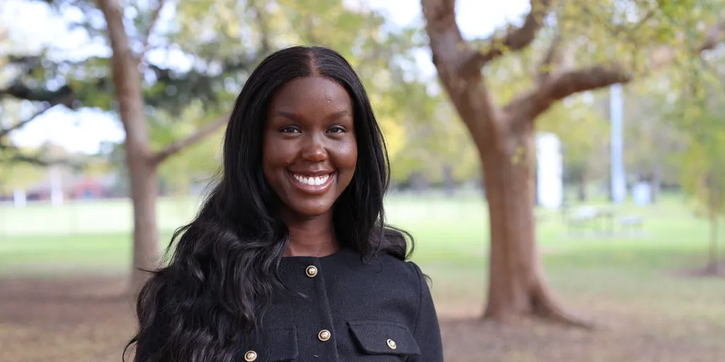 Paraman Tot is photographed standing in a park, wearing a navy jacket