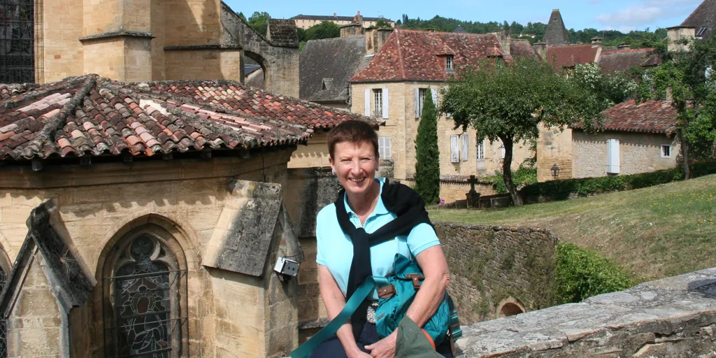 Australia for UNHCR bequestor Stephanie sits smiling on an old stone wall